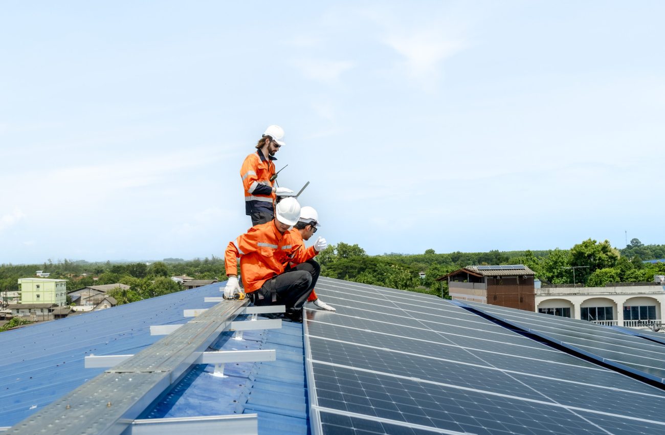 engineer man inspects construction of solar cell panel or photovoltaic cell by electronic device. Industrial Renewable energy of green power. factory worker working on tower roof.